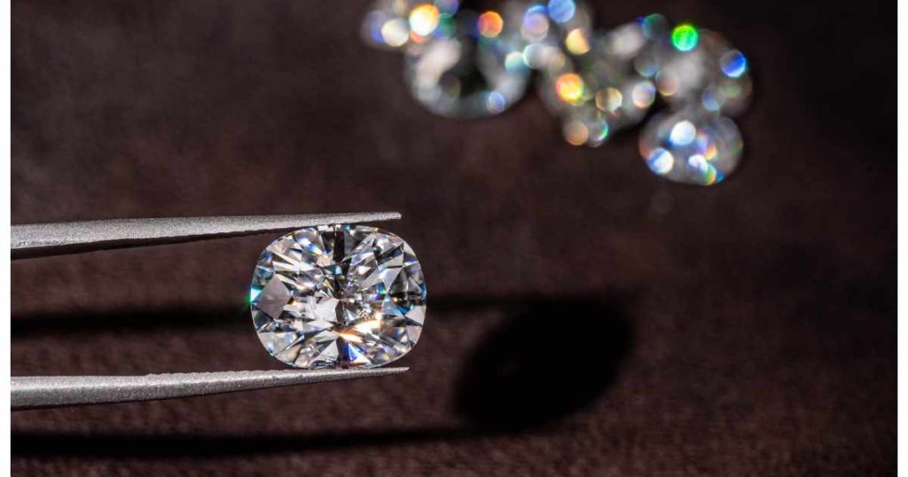Close-up of a sparkling diamond held by jeweler’s tweezers, with blurred diamonds in the background