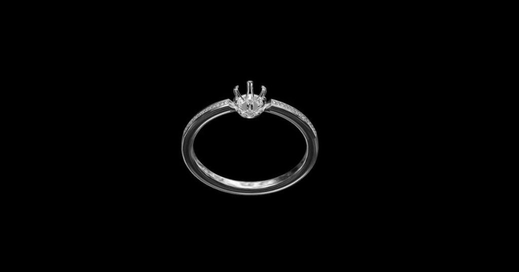 Close-up of a white gold or platinum engagement ring setting without the center stone, displayed against a black background.