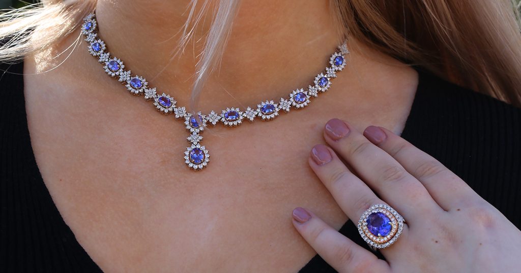 Woman wearing Sophia Fiori tanzanite necklace and ring set with vibrant blue-violet gemstones surrounded by diamonds, representing the December birthstone.