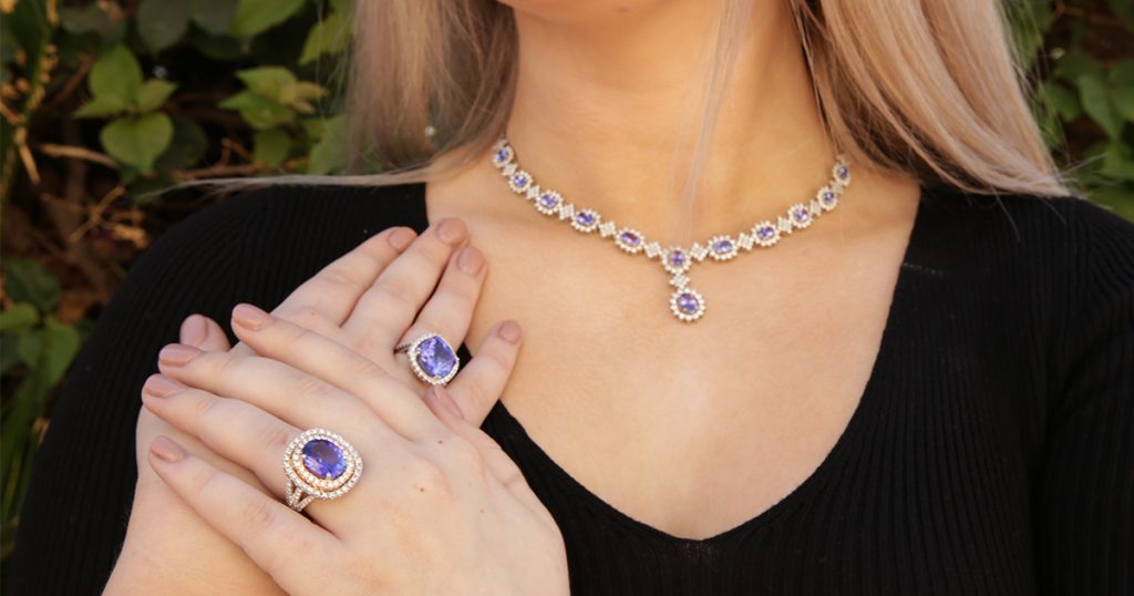 A sophisticated look featuring a Tanzanite and diamond necklace matched with statement rings. The deep violet hues sparkle under natural light, a testament to fine jewelry artistry.